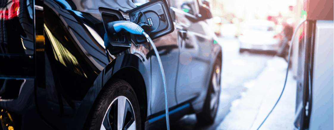 black SUV with a blue EV charger plugged into it