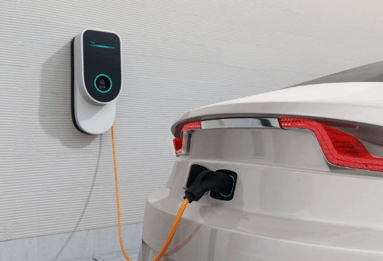 White car using a small ev charger which is mounted to the wall.